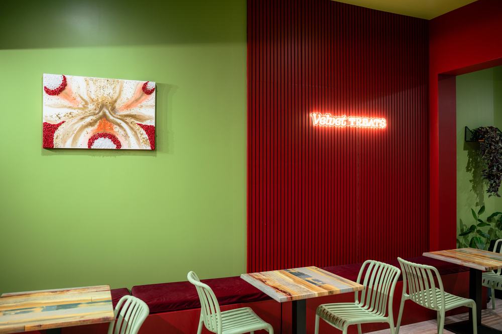 Framed dessert artwork on the green wall beside the red feature wall