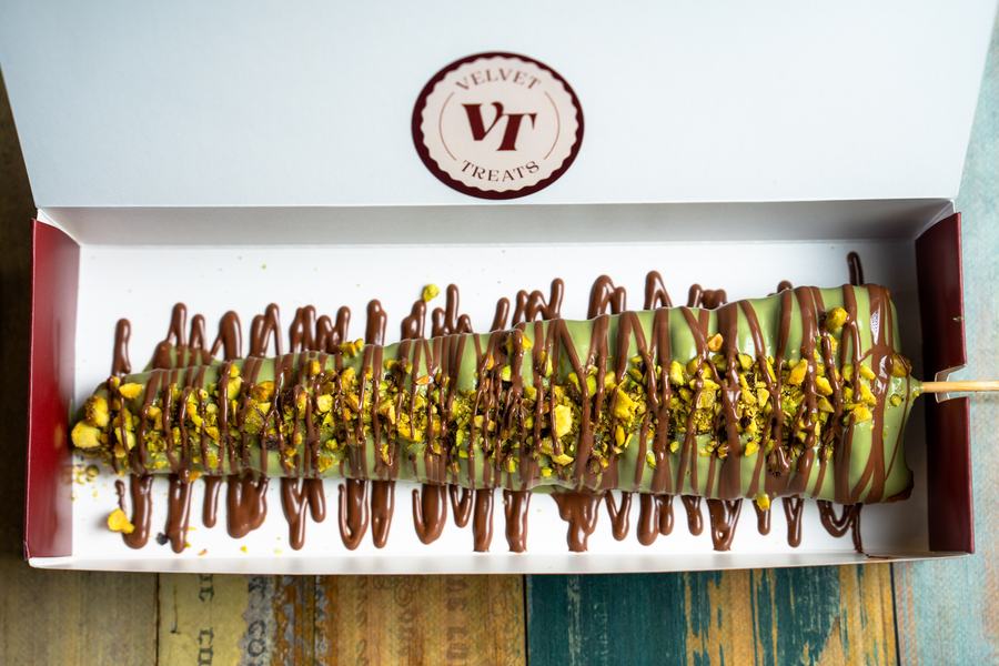 A Velvet Wand dipped in pistachio and chocolate, topped with crushed pistachio